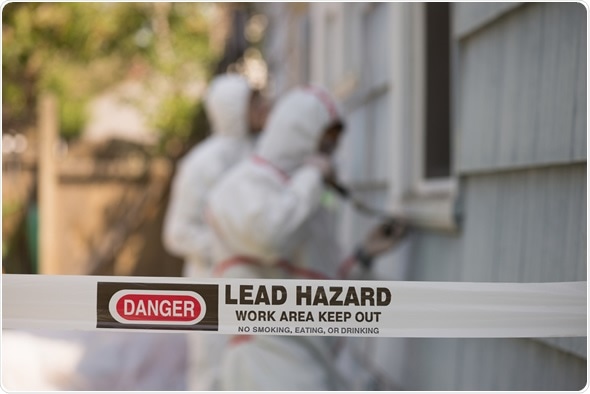 Two house painters in hazmat suits removing lead paint from an old house. Image Copyright: Jamie Hooper / Shutterstock