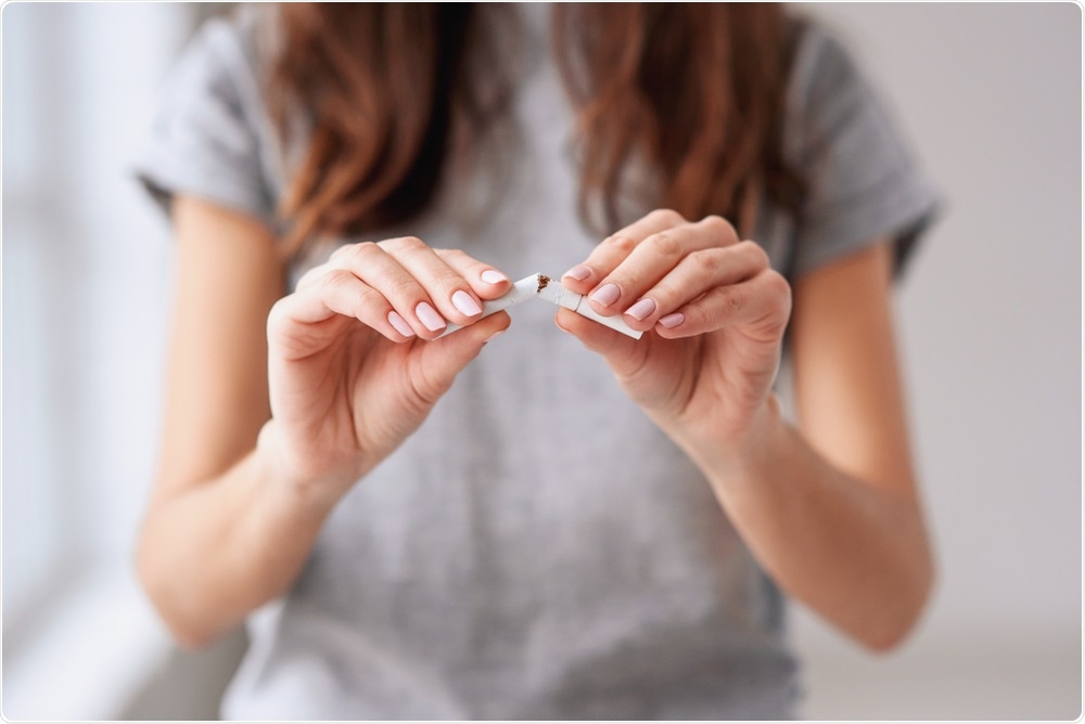 Woman splitting cigarette in half to throw away.