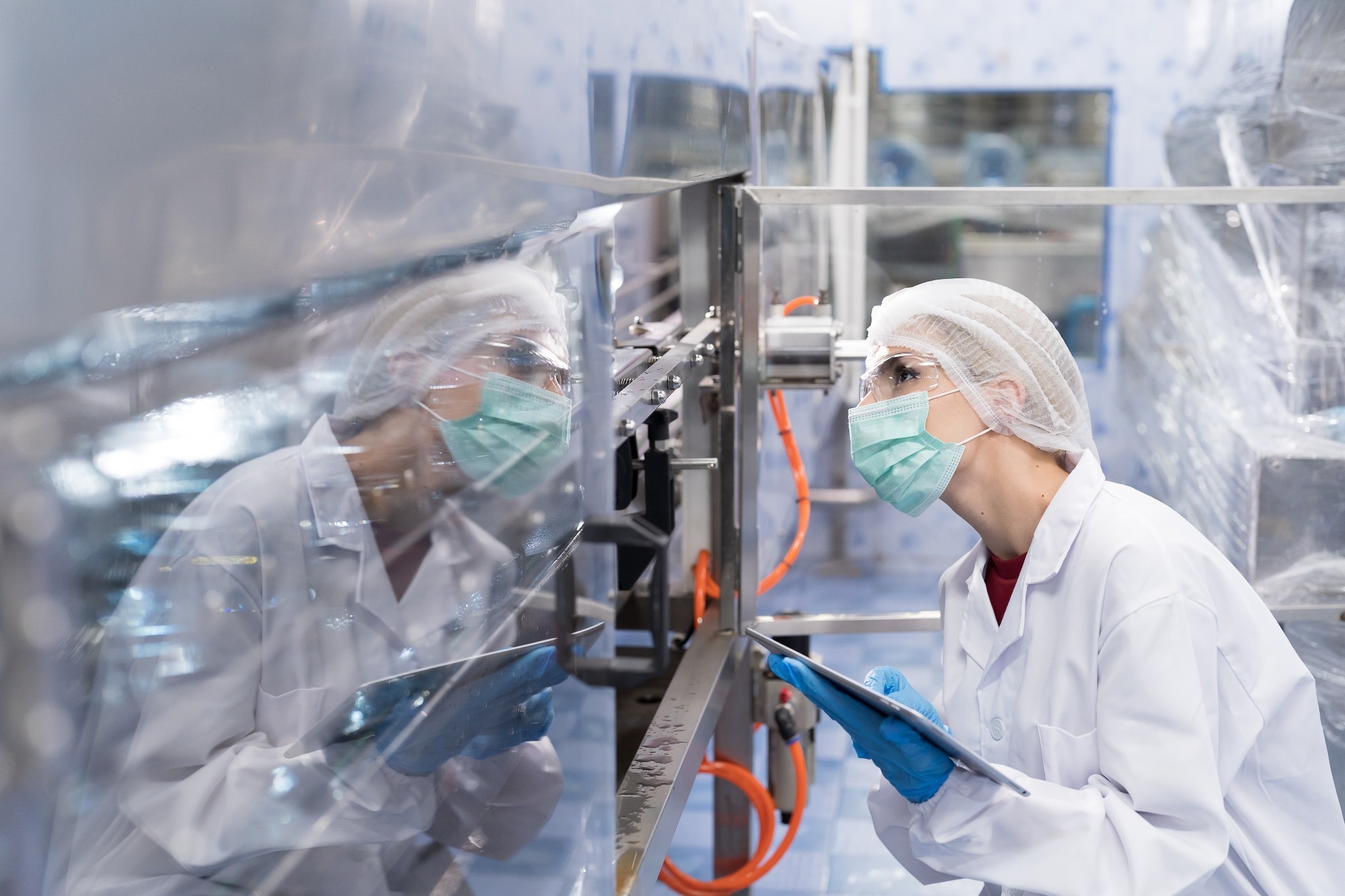 Female worker produces inspecting quality of plastic water tank on conveyor belt in drinking water factory. Worker using tablet working and checking bottle or gallon on conveyor production line