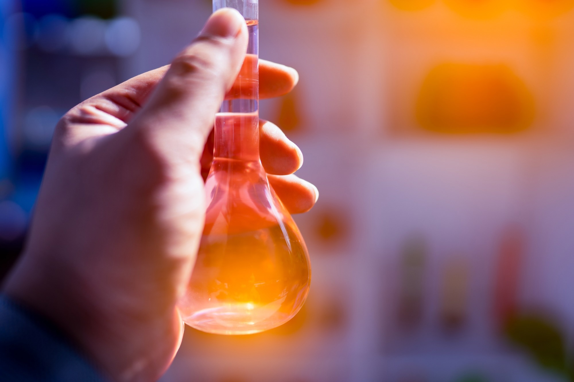 colorful chemical solution in flask on hand of scientist