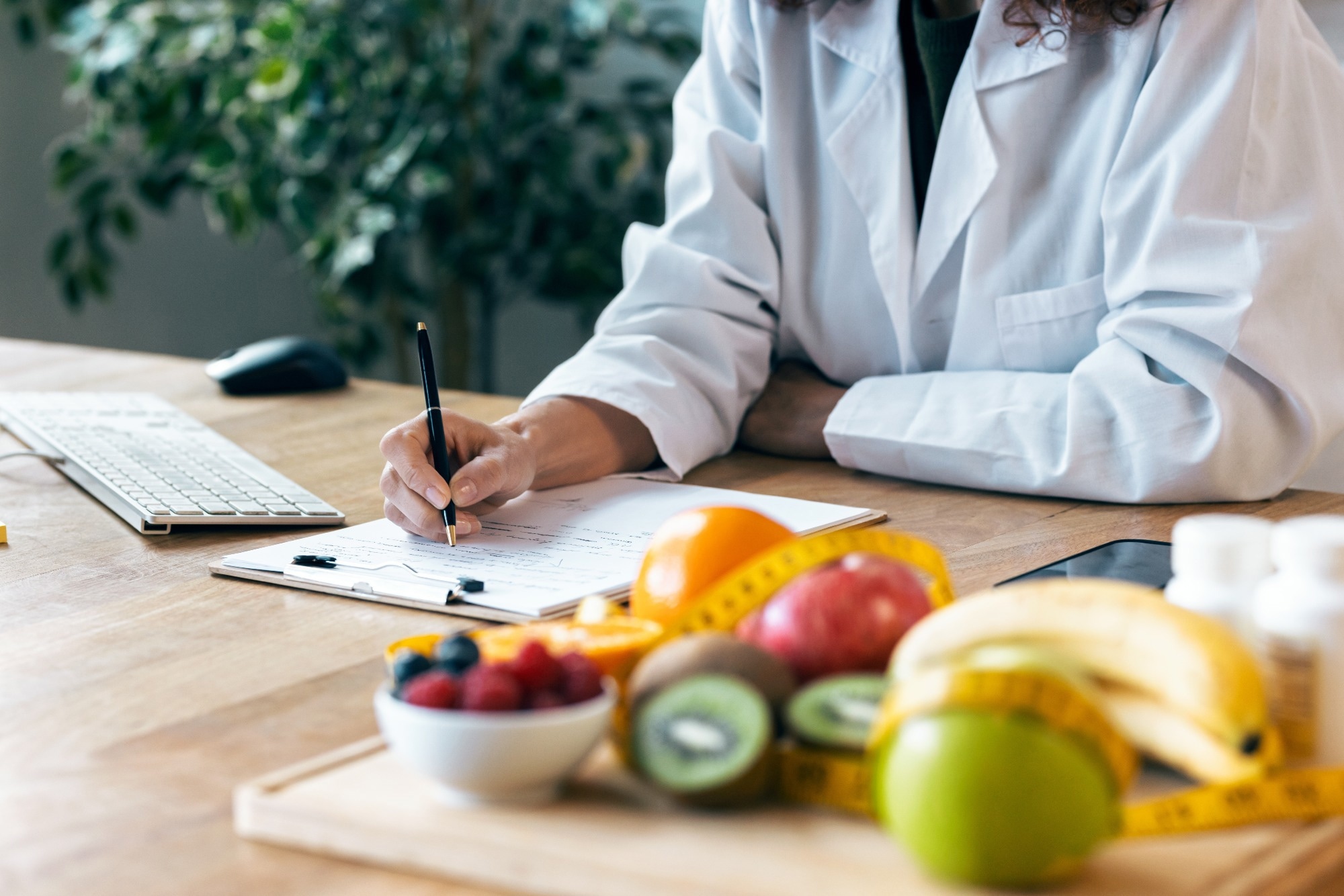 Clinician writing on notepad near fruits.