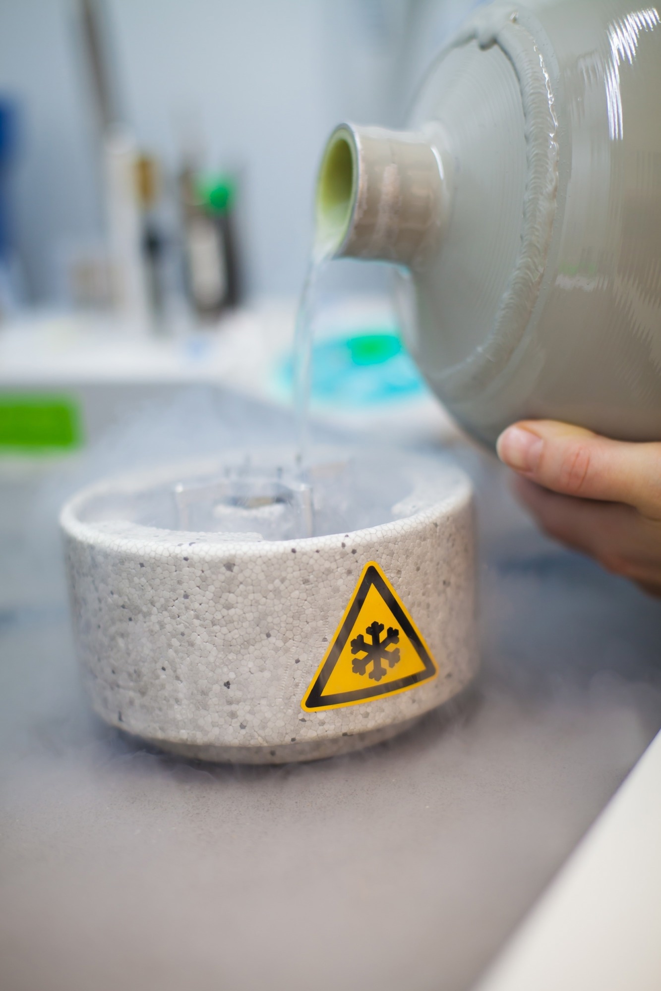 Cryogenic liquid being poured into an insulated laboratory container.