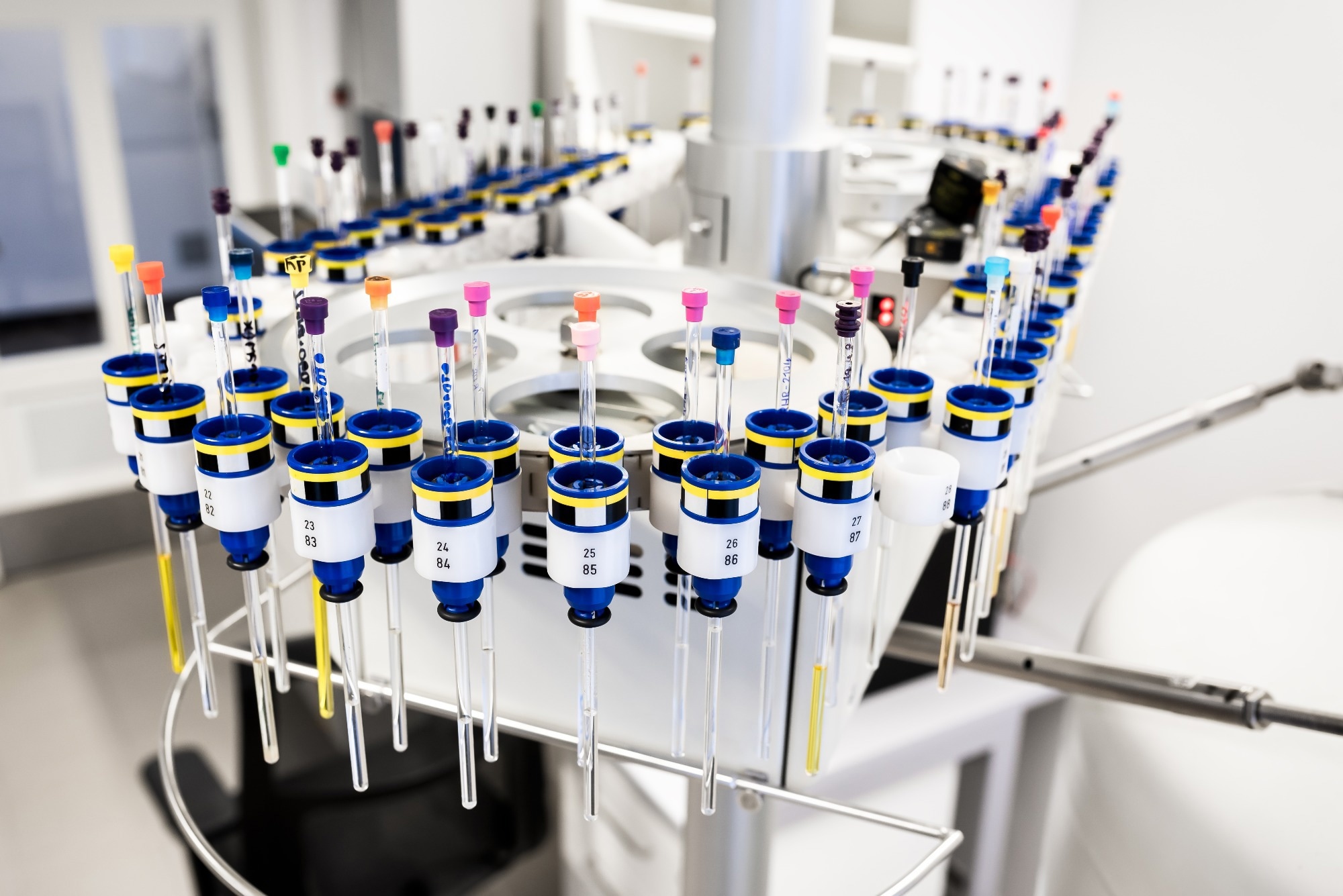 Automated laboratory sample carousel holding multiple tubes for sequential analysis.