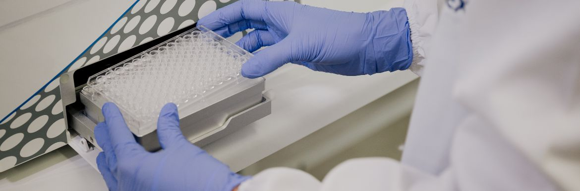 A scientist holds a box of micropipette tips with blue nitrile gloves.