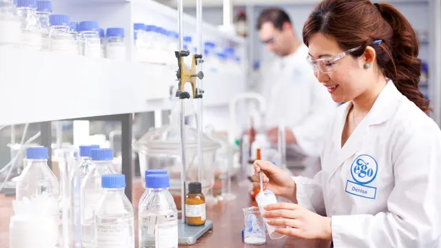 An ego pharmaceuticals chemist pipettes a sample in a lab.