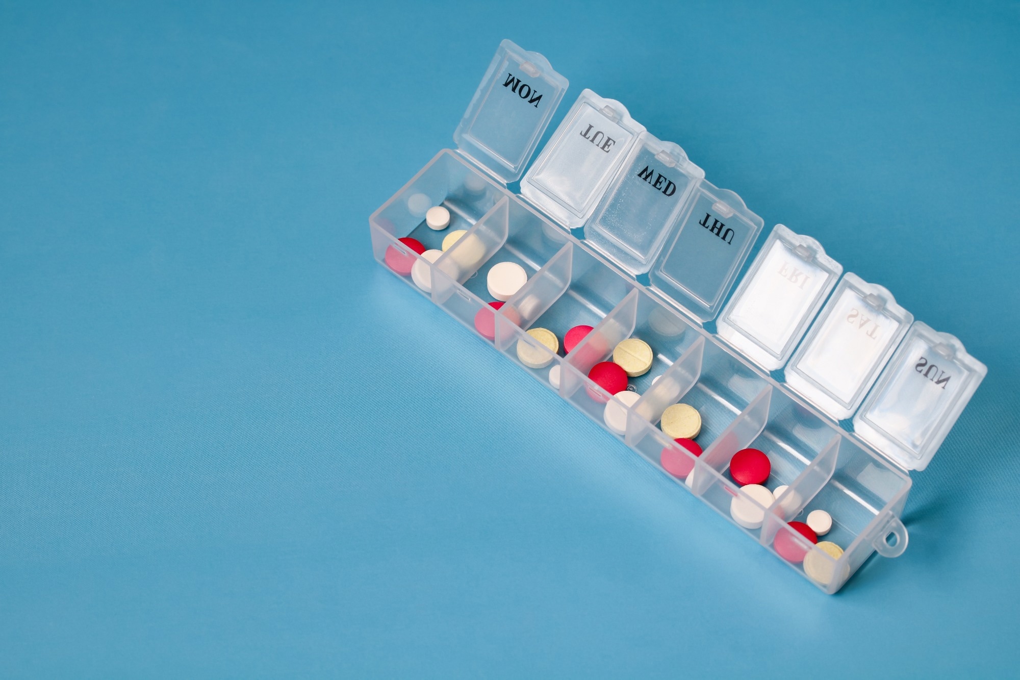 Daily pill box with various pills and tablets for managing medication schedule. medical background with space for text