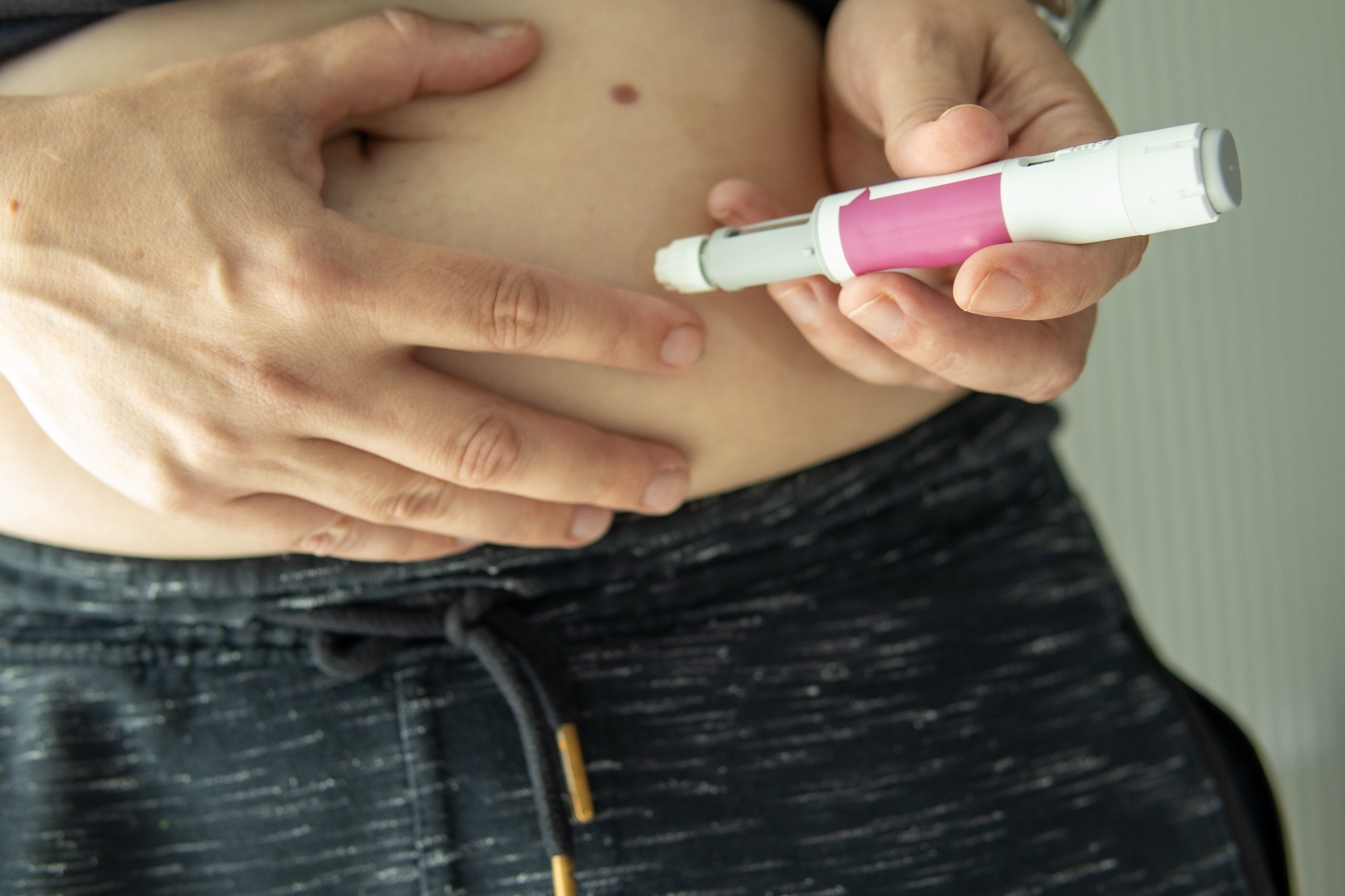 A person prepares to inject semaglutide with a pen into their abdomen.