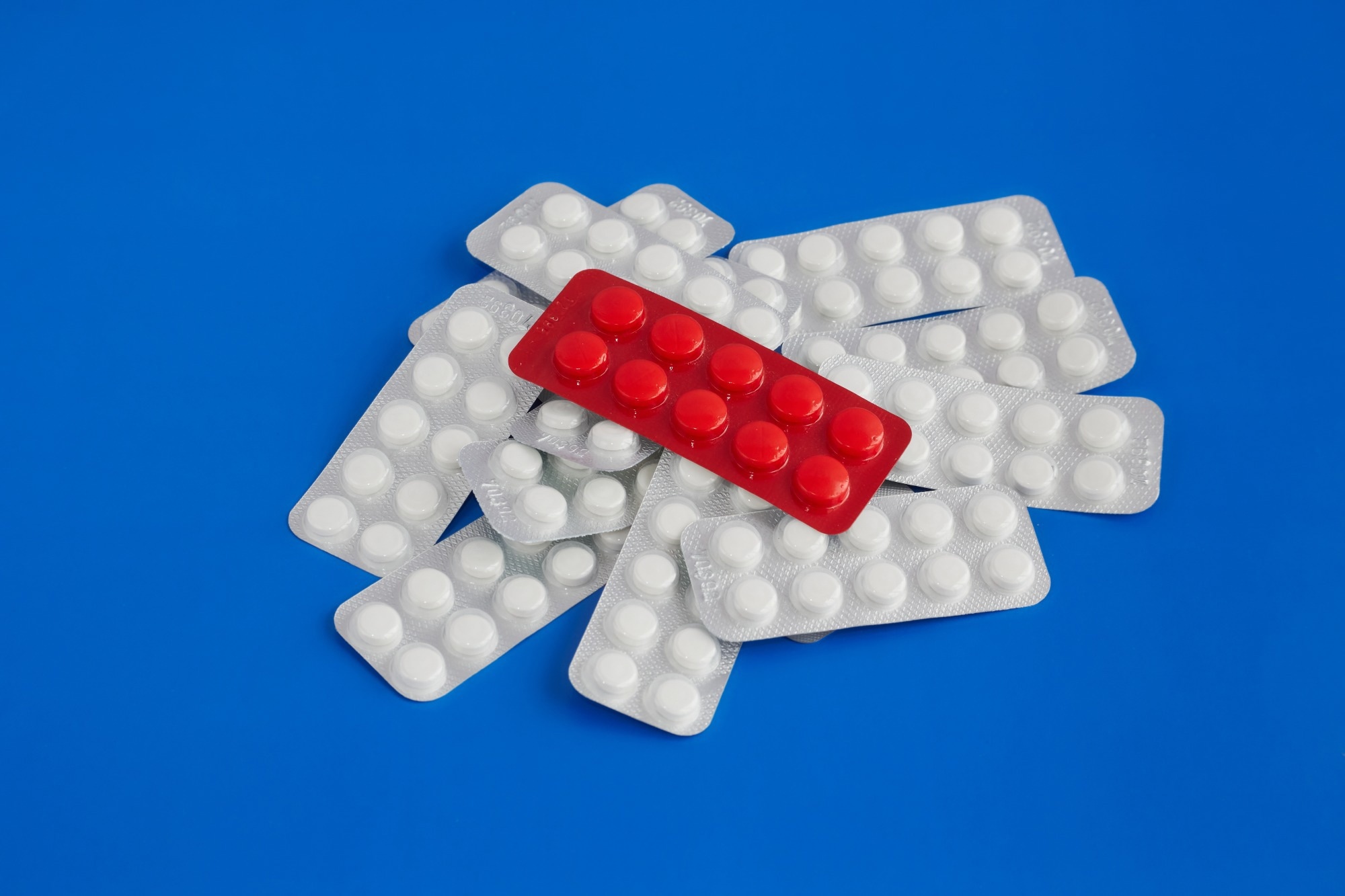 red blister pack of pills on top of a pile of white blister packs of pills, effective treatment, choice of medications, placebo effect