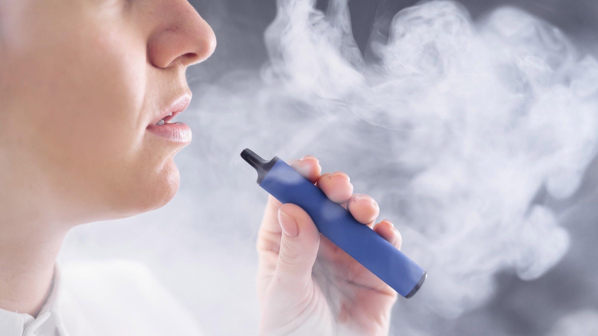 Caucasian woman smokes a disposable vape in the studio.
