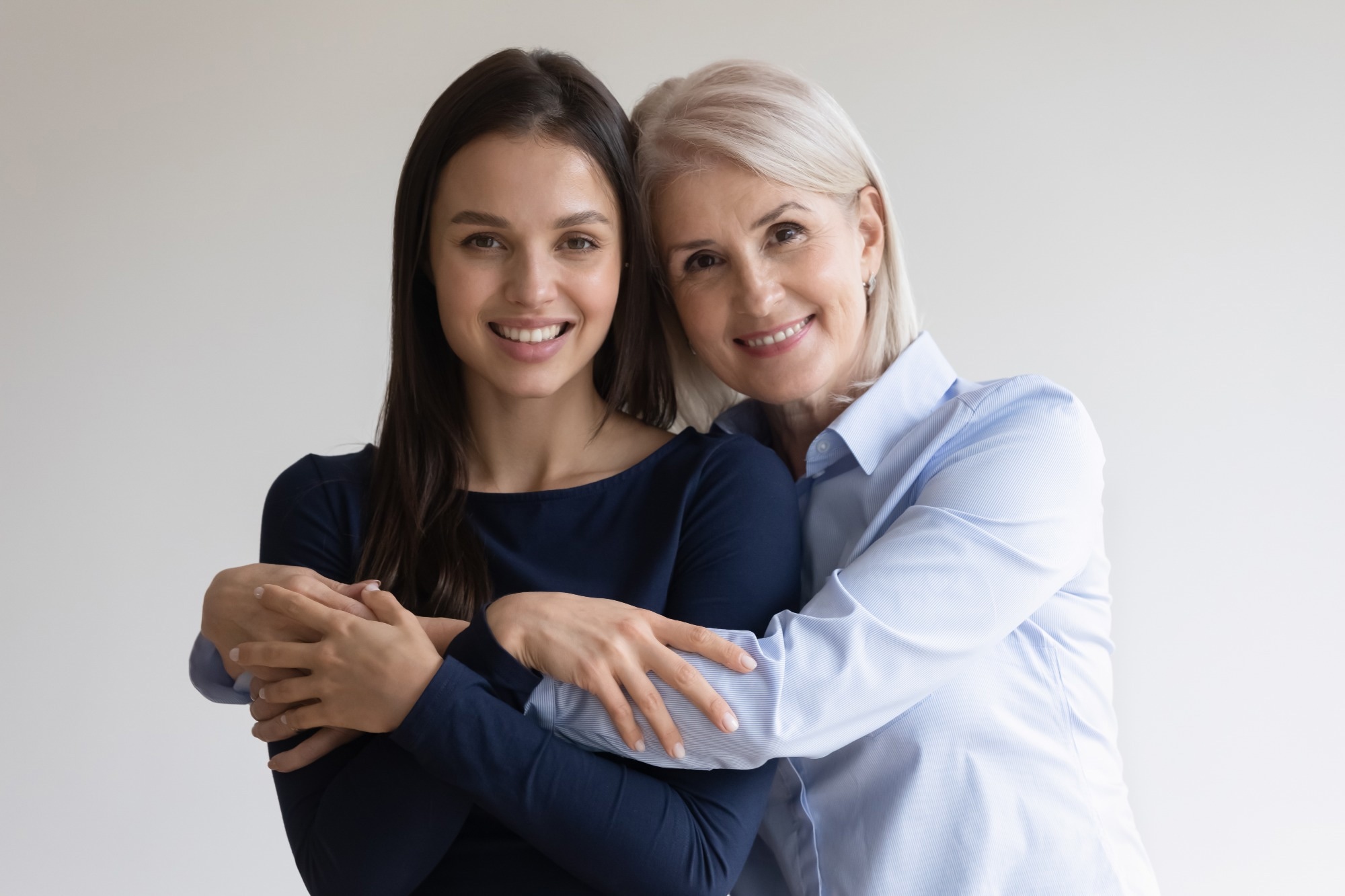 Portrait of smiling mature mother and beautiful millennial daughter hug look at camera posing together
