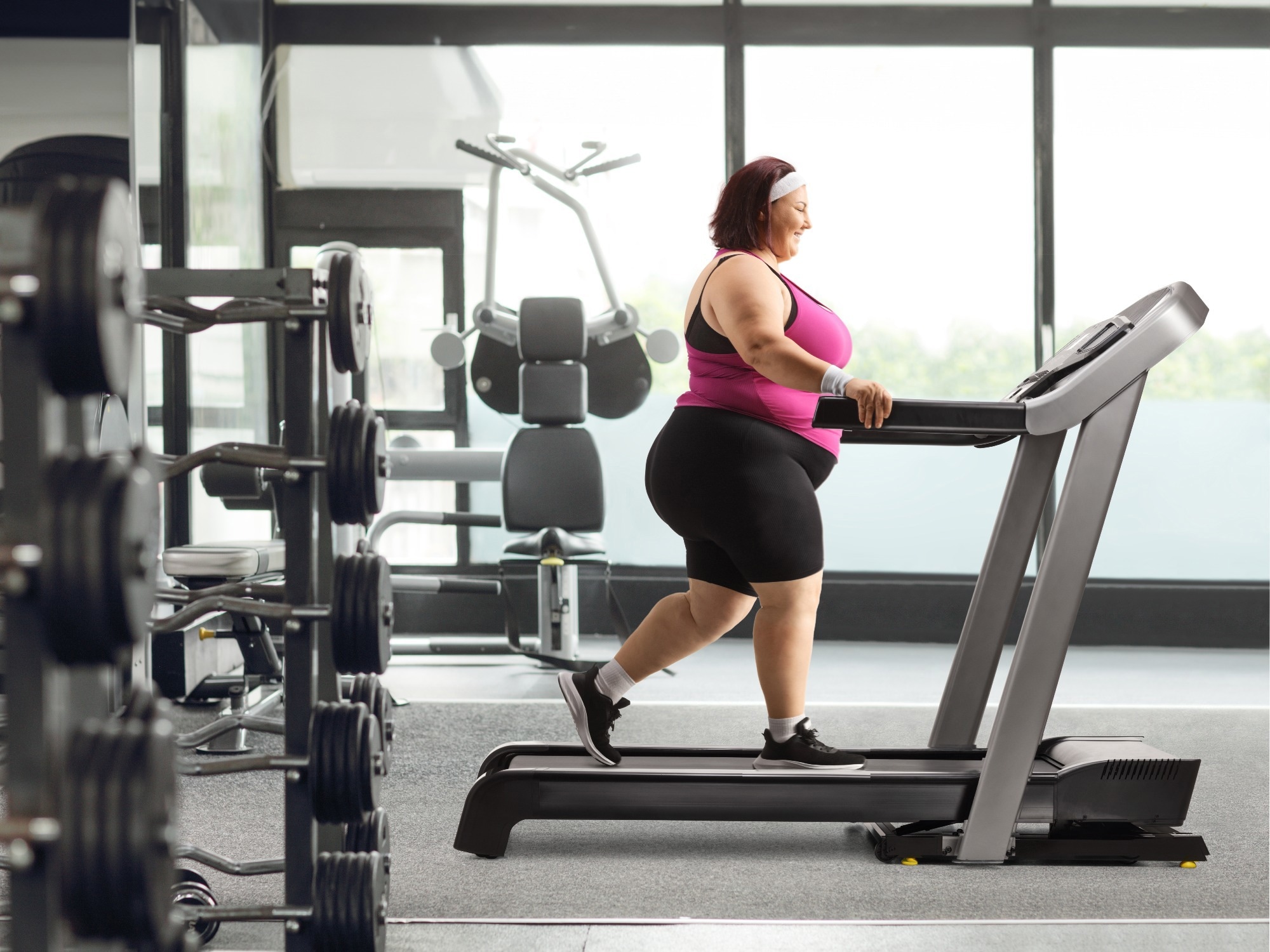 Overweight woman walking on a treadmill at the gym