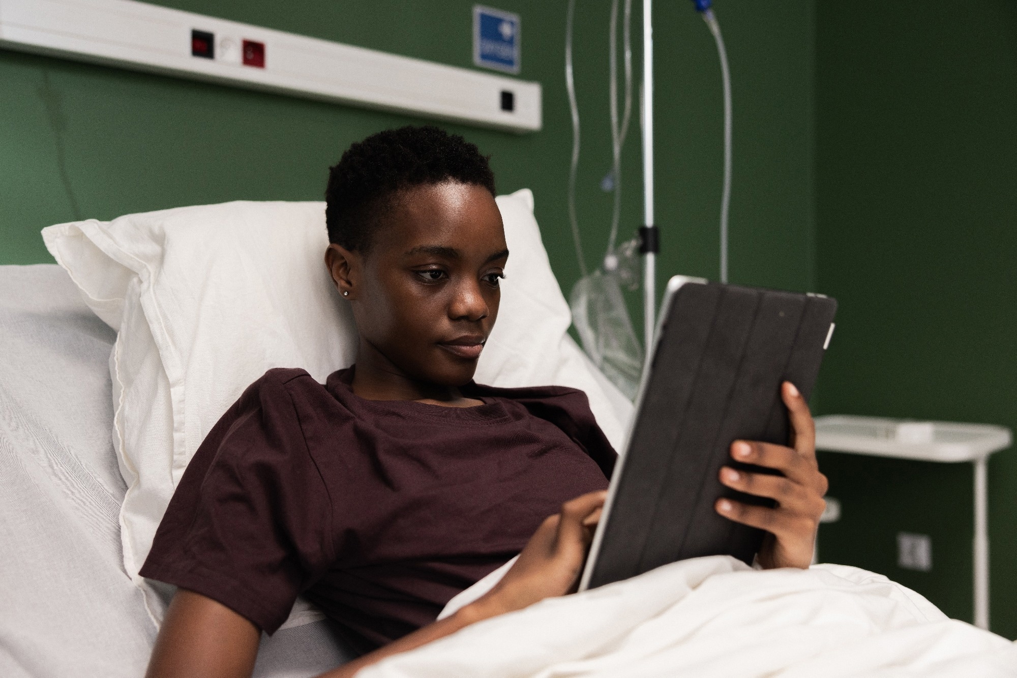 Teen boy in hospital bed using iPad