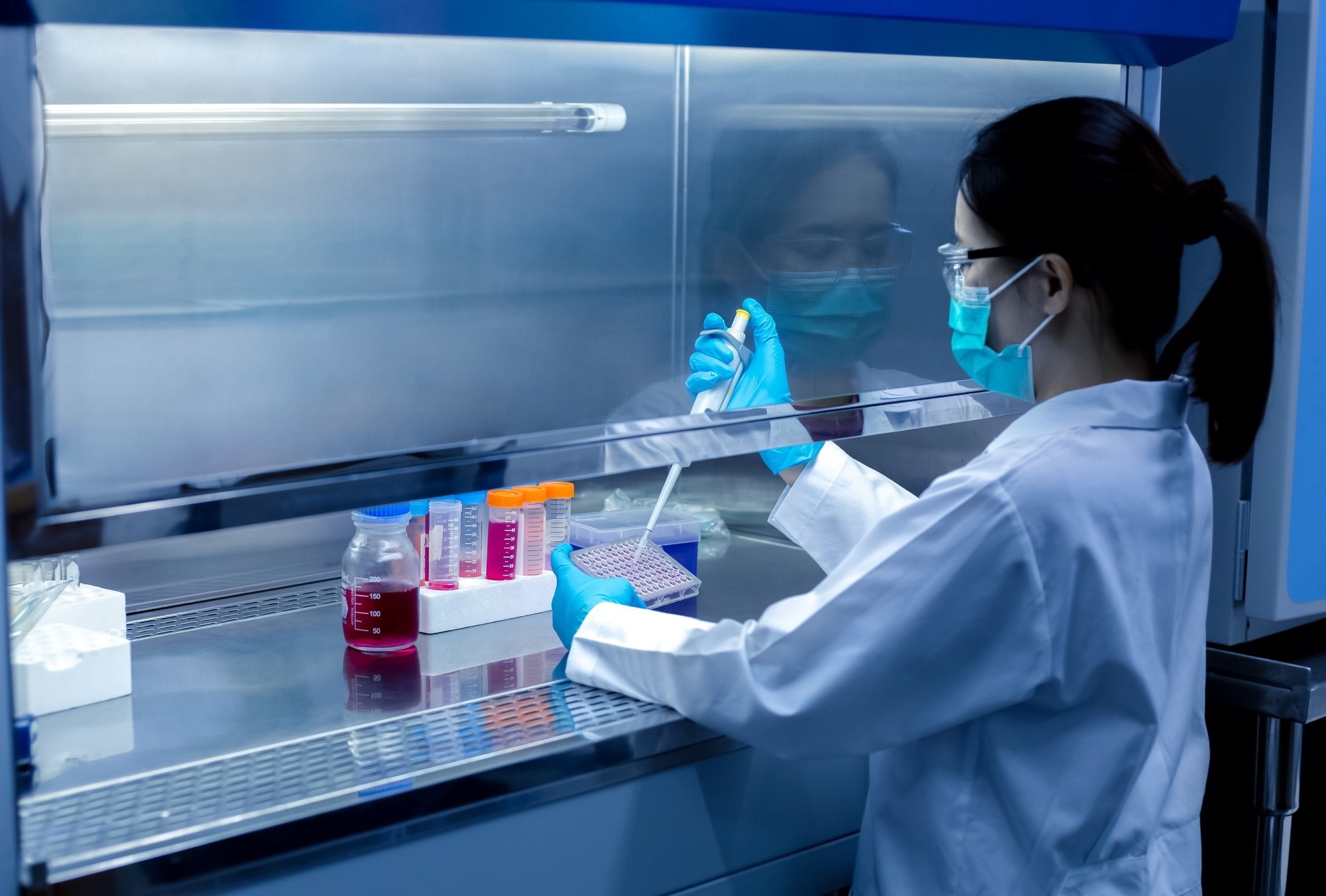 Scientist performing an in vitro assay in a laboratory using a pipette and multiwell plate for drug safety testing.