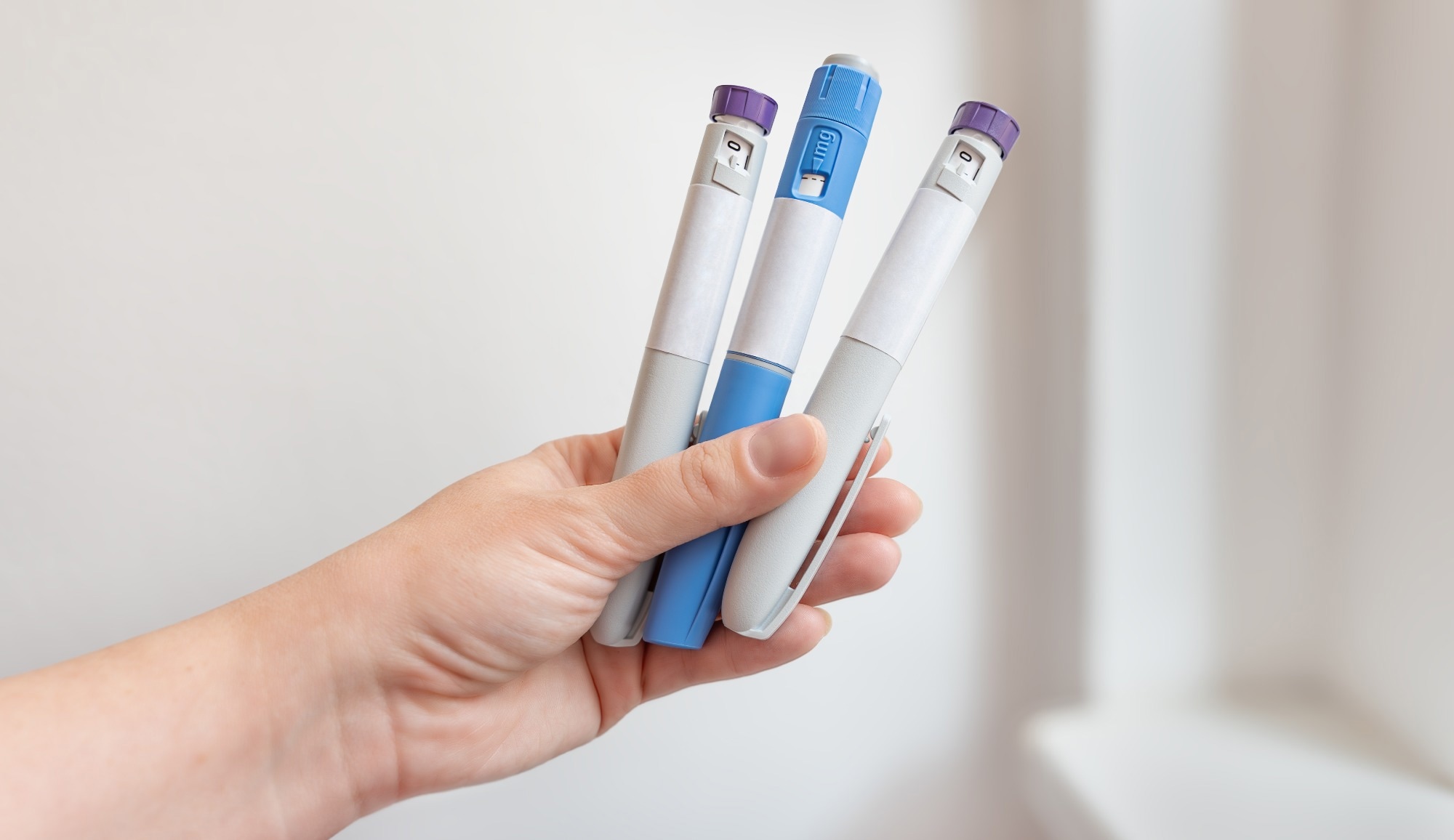 Close-up of a hand holding several GLP-1 injection pens. Concept of modern treatment for diabetes and weight loss therapy, pharmaceutical medication and healthcare innovation.