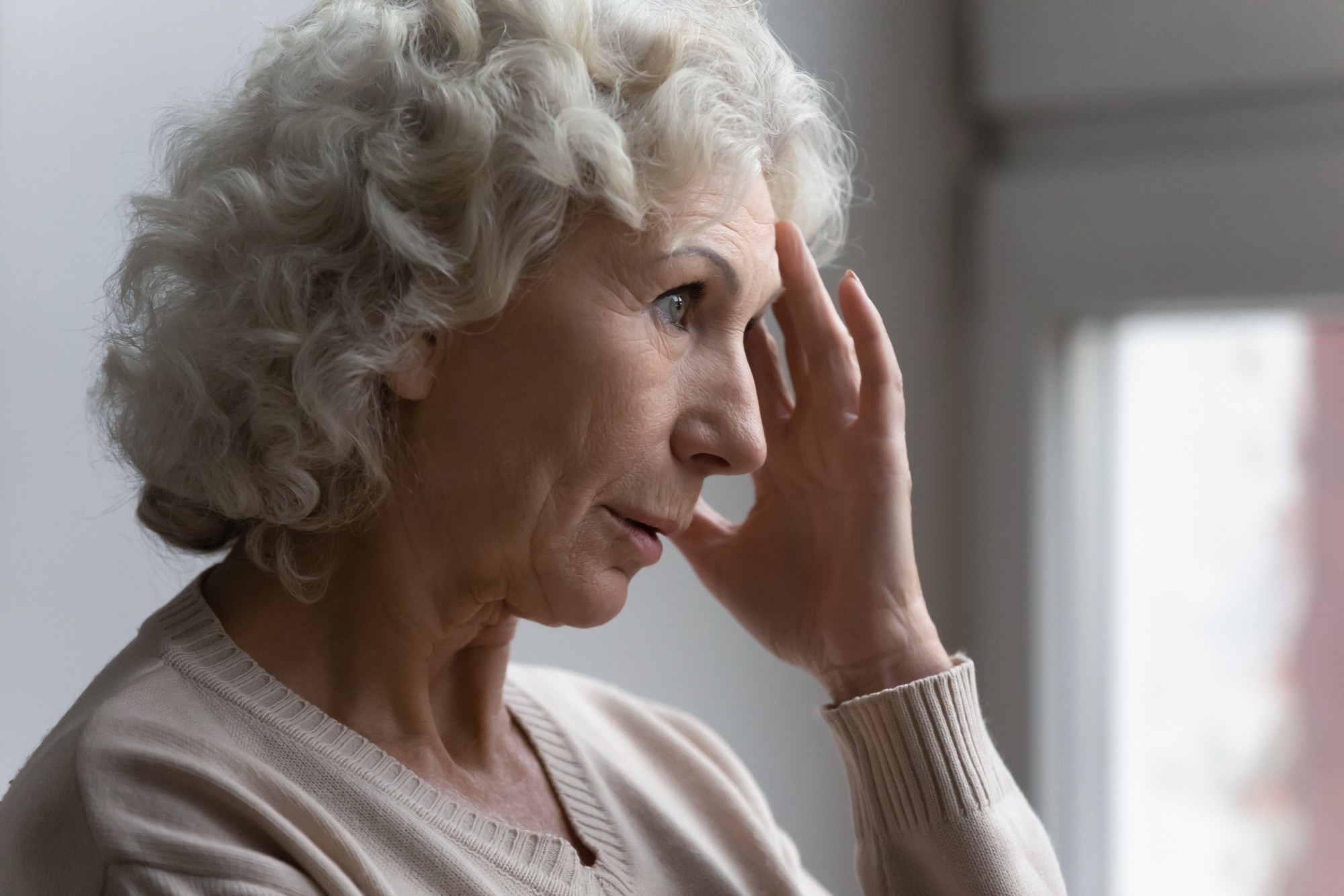 Concerned pensive senior 70s woman feeling anxiety. Hand to head temple