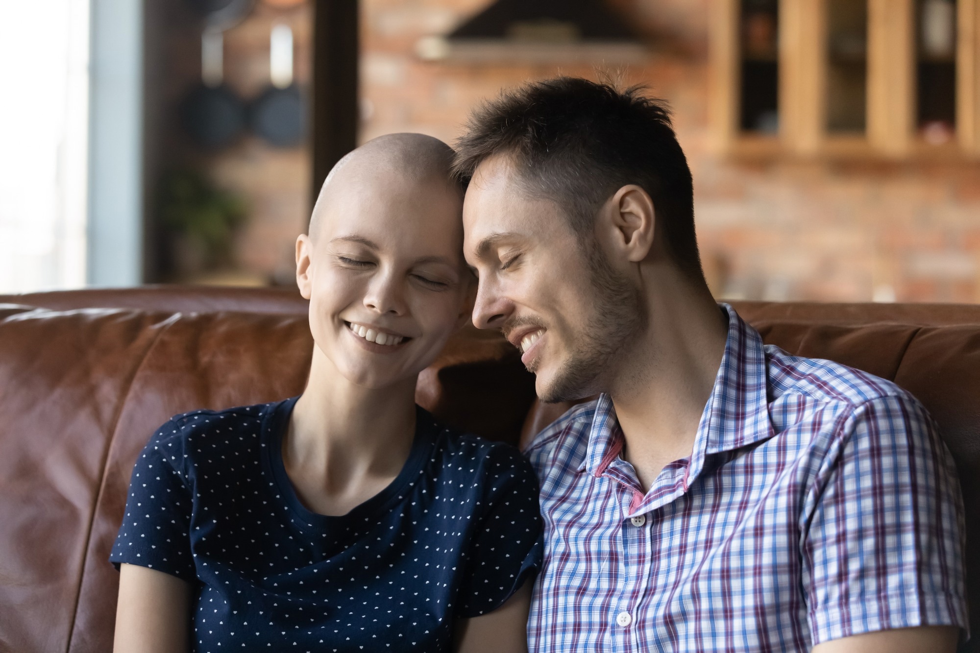 Caring young Caucasian man sit on couch hug comfort sick cancer patient